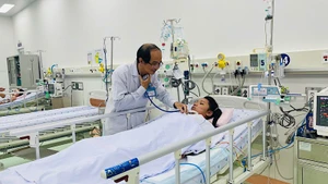Phó Giáo sư, Tiến sĩ, bác sĩ Phạm Văn Quang, Trưởng khoa Hồi sức tích cực-Chống độc, Bệnh viện Nhi đồng 1 khám bệnh nhi nữ 12 tuổi từ Trà Vinh. (Ảnh: CHI MAI)