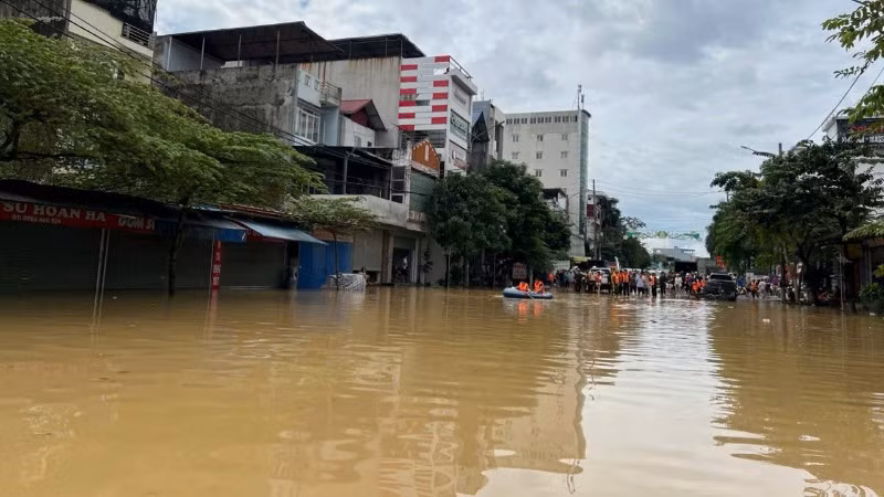 Ngập úng tại khu vực ngã tư san nền, phường Phan Đình Phùng. Phía xa là lực lượng chức năng, người dân tập trung hỗ trợ các thuyền đón người từ vùng ngập ra. (Ảnh: TUẤN SƠN).