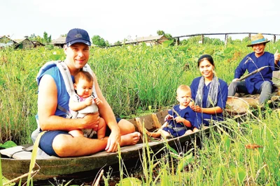 Du khách trải nghiệm đi xuồng khi nước lũ vừa vào đồng.