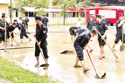 Các lực lượng Công an, quân sự dọn bùn sau khi nước lũ rút.