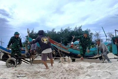 Cán bộ, chiến sĩ Đồn Biên phòng Roòn (Quảng Trị) giúp dân kéo, chuyển thuyền đánh cá lên bờ.