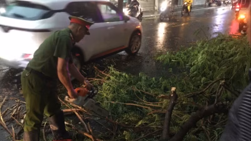 Công an phường Tây Hồ thu dọn cây xanh bị gãy đổ gây cản trở giao thông trên đường phố. (Ảnh: HỒNG NHUNG)