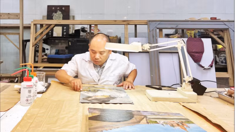 Ông Nguyễn Mạnh Hải làm sạch bức tranh của danh họa Trần Văn Cẩn.