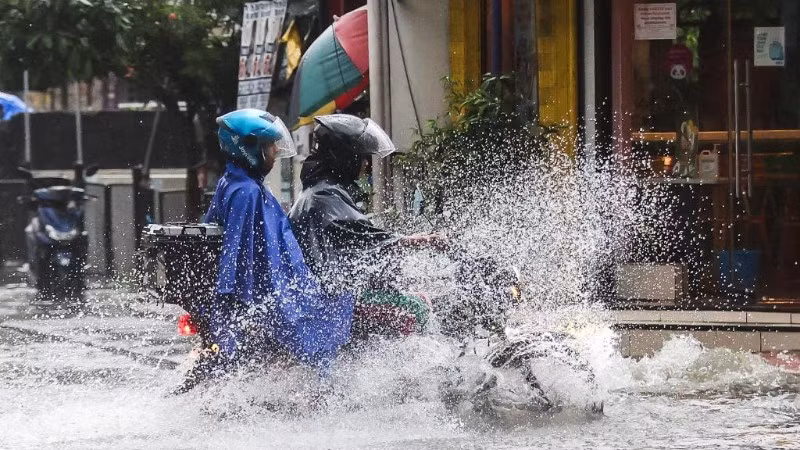 Người dân đi xe máy di chuyển qua con đường ngập nước ở thành phố Quezon, Philippines, vào ngày 19/7/2025. (Ảnh: XINHUA)
