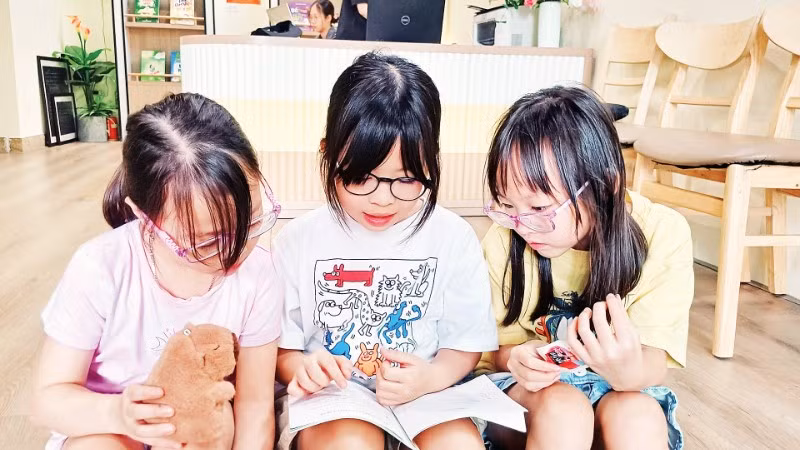 Các em nhỏ đọc sách để chuẩn bị cho cuộc thi trực tuyến. (Ảnh: MAI LỮ)