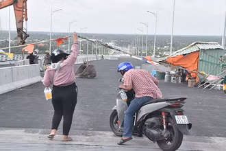 Người dân nâng dây để đi qua cầu Rạch Miễu 2.