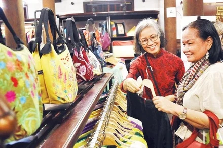 Khách du lịch mua hàng tại một cửa hàng giới thiệu sản phẩm làng nghề dệt lụa Vạn Phúc.