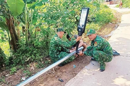 Cán bộ, chiến sĩ Đồn Biên phòng Bắc Xa lắp cột đèn năng lượng tại thôn Bản Hang, xã Kiên Mộc.
