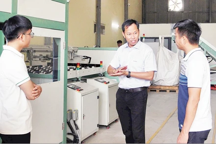 Tiến sĩ Đỗ Thế Cần (giữa) cùng cộng sự bên cạnh dây chuyền xử lý pin mặt trời.