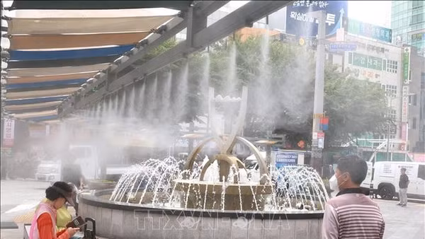 Người dân làm mát dưới đài phun nước khi nắng nóng gay gắt bao trùm thành phố Busan, Hàn Quốc ngày 29/5/2026. (Ảnh: YONHAP/TTXVN)
