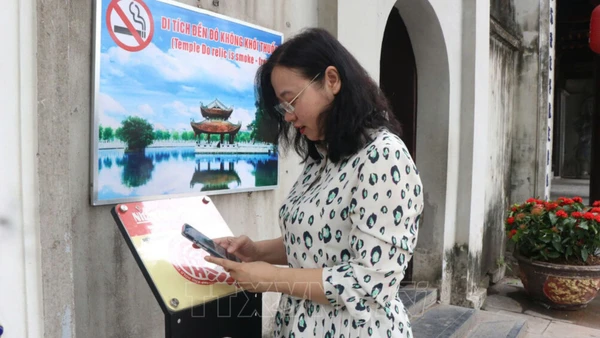 Du khách quét mã QR để trải nghiệm hành trình tham quan được số hóa tại Di tích đền Đô. (Ảnh: TTXVN)