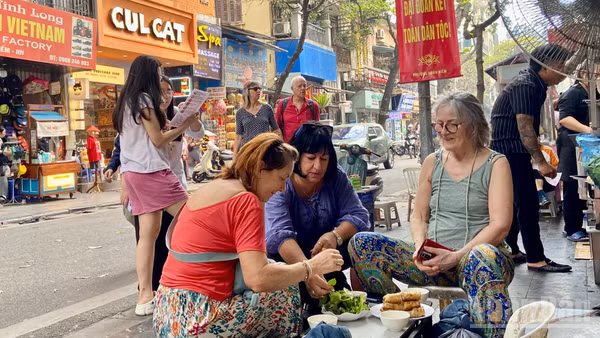 Khách quốc tế thưởng thức ẩm thực đường phố khi tham quan Hà Nội. (Ảnh: CHIÊU ANH)