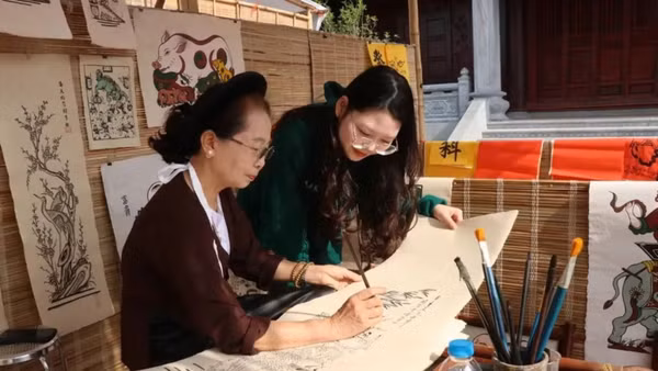 Du khách tìm hiểu quy trình làm tranh dân gian Đông Hồ. (Ảnh: TTXVN)