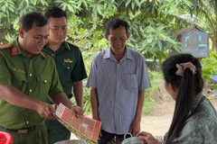 Trung tá Châu Văn Nát phát tờ rơi tuyên truyền cho người dân các phương thức tội phạm mới để nâng cao cảnh giác.