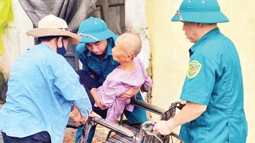 Chính quyền địa phương giúp đỡ những người già yếu, tàn tật sơ tán khỏi mưa lũ. 