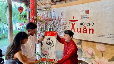Một "thầy đồ" hiện đại trao bức thư pháp chữ quốc ngữ tặng du khách nước ngoài trong ngày đầu Xuân tại Văn Miếu-Quốc Tử Giám (Hà Nội). 