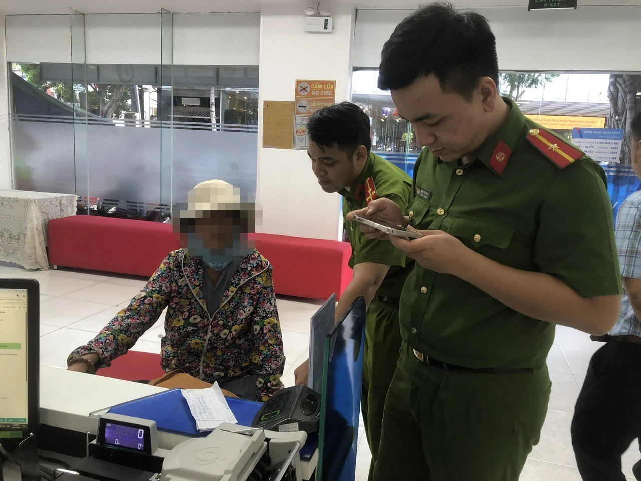Lực lượng chức năng hướng dẫn bà N chuyển gửi tiết kiệm số tiền 300 triệu đồng cho ngân hàng. (Ảnh: Công an cung cấp)