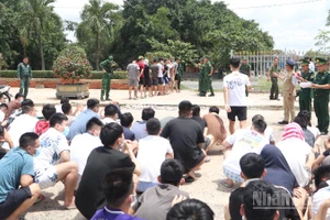 Lực lượng chức năng Việt Nam tiếp nhận các công dân liên quan tội phạm lừa đảo trực tuyến do phía Campuchia bàn giao tại khu vực cửa khẩu Mộc Bài. (Ảnh: ĐINH TRƯỜNG)