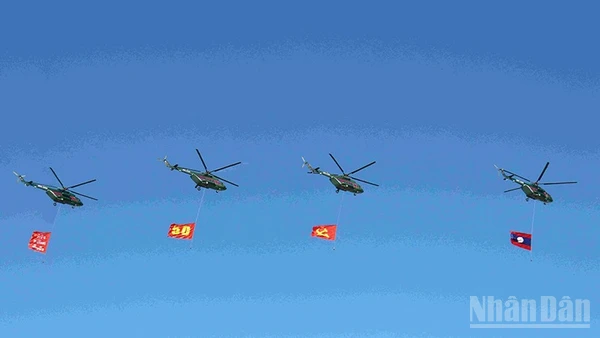 Đội hình máy bay trực thăng mang cờ Đảng, cờ Tổ quốc Lào trên bầu trời quảng trường That Luang. (Ảnh: DUY TOÀN)