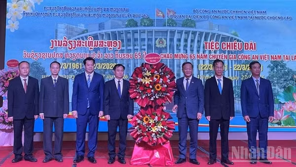 Đại sứ Nguyễn Minh Tâm (thứ 3 từ phải qua) tặng hoa chúc mừng đội ngũ Chuyên gia Công an Việt Nam tại Lào. (Ảnh: DUY TOÀN)