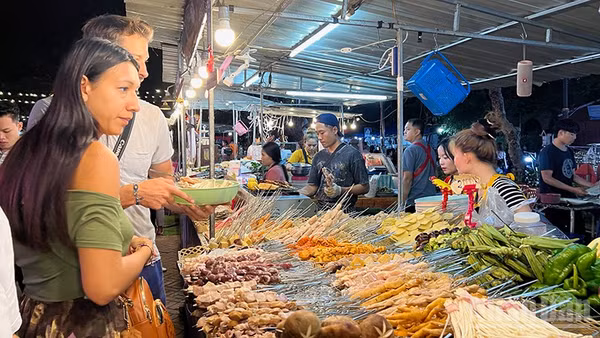 Ảnh minh họa: Khách du lịch nước ngoài hào hứng khám phá các món ăn Lào. (Ảnh: TRỊNH DŨNG)