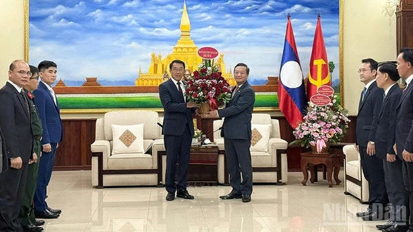 Đại sứ Nguyễn Minh Tâm trao lẵng hoa tươi thắm tới đồng chí Bounleua Phandanouvong, Trưởng Ban Đối ngoại Trung ương Đảng Nhân dân Cách mạng Lào. (Ảnh: Cộng tác viên)