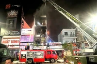 Các chiến sĩ dùng thang xếp leo lên các nhà dân bên cạnh tiếp cận đám cháy.