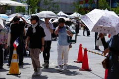 Người dân di chuyển trên đường phố dưới trời nắng nóng tại Osaka, Nhật Bản. (Ảnh: TTXVN)