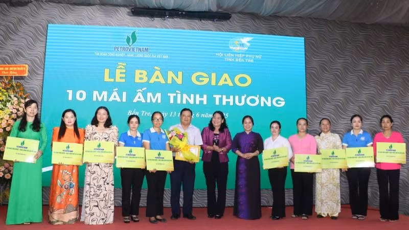 Đại diện Báo Nhân Dân trao bảng tượng trưng bàn giao 10 căn nhà mái ấm tình thương cho phụ nữ có hoàn cảnh khó khăn trên địa bàn. (Ảnh: HOÀNG TRUNG)