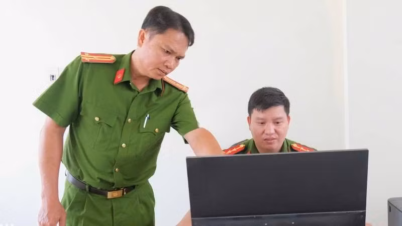 Thượng tá Cao Thành Nhân (trái) hướng dẫn cán bộ hoàn chỉnh hồ sơ quản lý địa bàn. (Ảnh: Đăng Khoa)