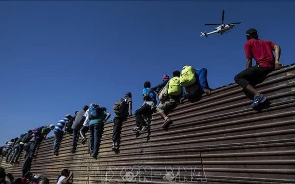Người di cư trèo qua bức tường biên giới Mexico-Mỹ, gần cửa khẩu El Chaparral ở Tijuana, bang Baja California, Mexico. (Ảnh tư liệu: TTXVN)