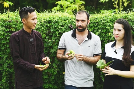 Anh Hoàng giới thiệu với khách nước ngoài về công dụng của quả mướp đắng rừng.