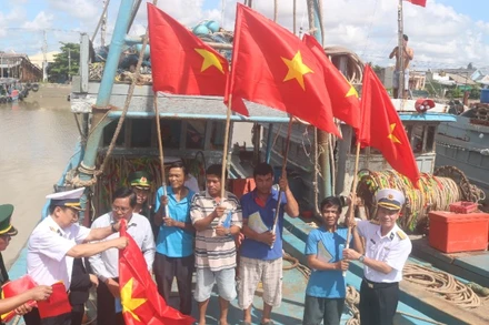 Ngư dân xã Đại An, tỉnh Vĩnh Long được cán bộ, chiến sĩ Hải quân Vùng 2 trao tặng cờ Tổ quốc.