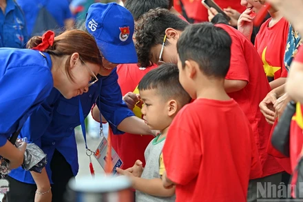 Các nữ tình nguyện viên hỗ trợ một em nhỏ trên địa bàn phường Cửa Nam (thành phố Hà Nội).
