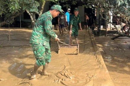 Cán bộ, chiến sĩ Bộ đội Biên phòng tỉnh Nghệ An giúp đỡ nhân dân dọn dẹp bùn đất sau lũ.