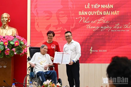 Tổng Biên tập Lê Quốc Minh nhận bản thảo bài hát Như có Bác trong ngày đại thắng có chữ ký đề tặng của nhạc sĩ Phạm Tuyên. (Ảnh: THÀNH ĐẠT)