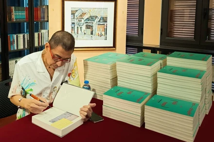 Họa sĩ Lê Thiết Cương ký sách "Trò chuyện về hội họa". (Ảnh: Nhà xuất bản Hội Nhà văn)