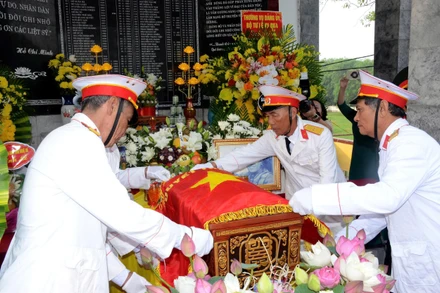 Các cựu chiến binh xã Thông Tân thực hiện nghi thức phủ Quân kỳ cho liệt sĩ Ngô Đức Mai. (Ảnh: THÀNH CHUNG)