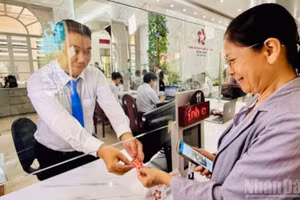 Bà Phùng Thị Nguyệt được cán bộ phường Sài Gòn tặng món quà lưu niệm nhỏ trong ngày đầu tiên vận hành mô hình chính quyền địa phương 2 cấp. (Ảnh: VƯƠNG LÊ)