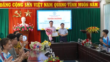 Đại diện lãnh đạo Trường Đại học Đồng Tháp Cao Dao Thép trao giấy khen và tiền thưởng cho em Nguyễn Minh Toàn. (Ảnh: HỮU NGHĨA)