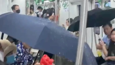 Hành khách phải che ô do nước từ điều hòa tàu chảy xuống sàn chiều 19/5. (Ảnh: cắt từ clip)