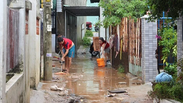 Người dân dọn dẹp bùn đất sau trận lụt.