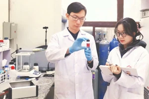 Tiến sĩ Nguyễn Nhật Linh hướng dẫn sinh viên kiểm tra mẫu sản phẩm hạt nano vàng thu được từ quá trình tổng hợp plasma. (Ảnh: MINH ĐỨC)