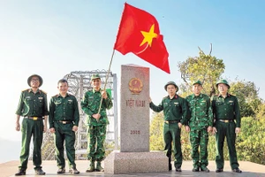 Thượng úy Lục Vĩnh Lương (người cầm cờ) cùng tác giả và đoàn công tác tại Cột mốc số 0 - Ngã ba biên giới A Pa Chải - Cực tây Tổ quốc.