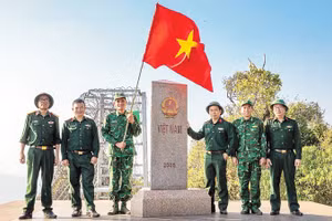 Thượng úy Lục Vĩnh Lương (người cầm cờ) cùng tác giả và đoàn công tác tại Cột mốc số 0 - Ngã ba biên giới A Pa Chải - Cực tây Tổ quốc.