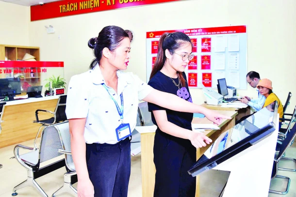 Cán bộ công chức Trung tâm Phục vụ hành chính công phường Hồng An, thành phố Hải Phòng hướng dẫn người dân thực hiện nộp hồ sơ trực tuyến. (Ảnh TRUNG KIÊN)