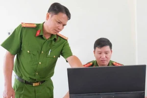 Thượng tá Cao Thành Nhân (trái) hướng dẫn cán bộ hoàn chỉnh hồ sơ quản lý địa bàn. (Ảnh: Đăng Khoa)