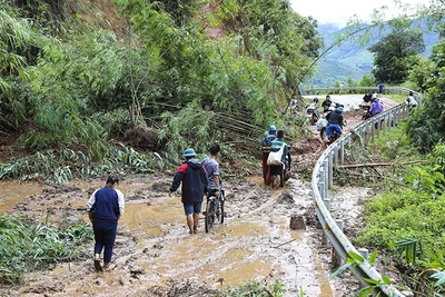 Người và xe máy vất vả di chuyển qua các điểm sạt lở tại Điện Biên. (Ảnh: TTXVN) 