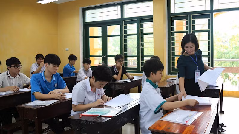 Giám thị phát giấy thi cho học sinh.