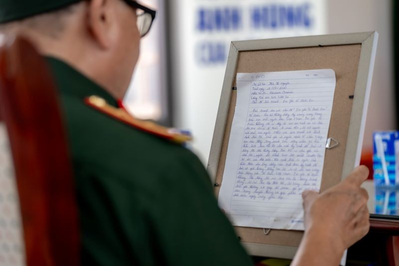 Các bác cựu chiến binh chăm chú đọc những dòng chữ nhỏ, được các em gửi kèm trong mỗi bức tranh. (Ảnh: DUY CƯỜNG) anh-4c.jpg
